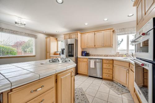 a large kitchen with wooden cabinets and appliances at 2 Mi to Badger Mountain Hot Tub Haven! in Richland