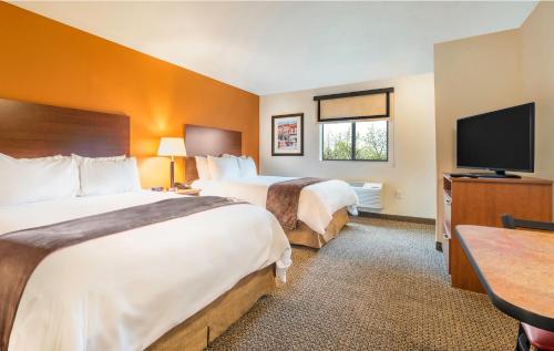 a hotel room with two beds and a flat screen tv at My Place Hotel Rapid City in Rapid City