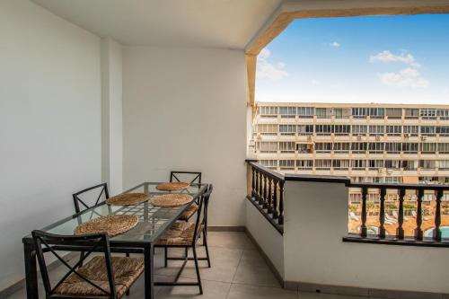 ein Balkon mit Tisch und Stühlen und einem großen Fenster in der Unterkunft Aguila Playa Beach Escape in Maspalomas