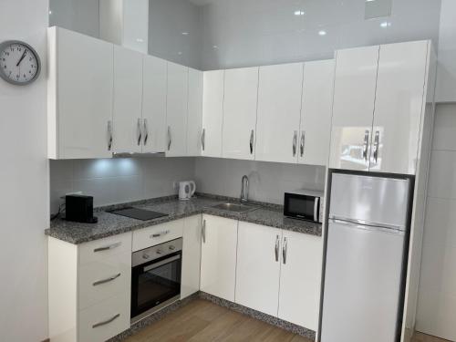 a kitchen with white cabinets and a clock on the wall at Apartamento Plaza España in Fuengirola