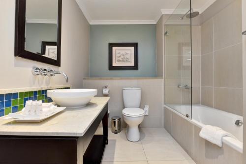 a bathroom with a sink and a toilet and a tub at Mount Grace Hotel & Spa in Magaliesburg