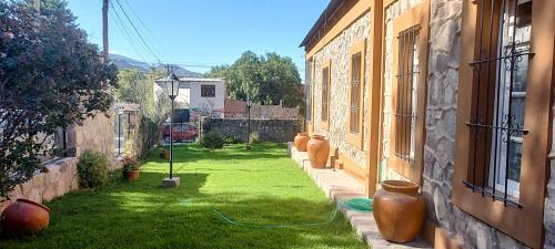 a yard with vases on the grass between two buildings at Estación Tilcara boutique hotel in Tilcara