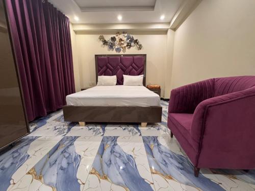 a bedroom with a bed and a purple couch at Blue Sky Hotel in Lahore