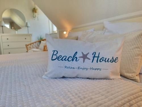 a bed with a beach house pillow on it at Düne 4 - Ferienunterkunft mit eigenem Garten in der beliebten Dünenresidenz - sanftes Meeresrauschen inklusive in Ostseebad Karlshagen