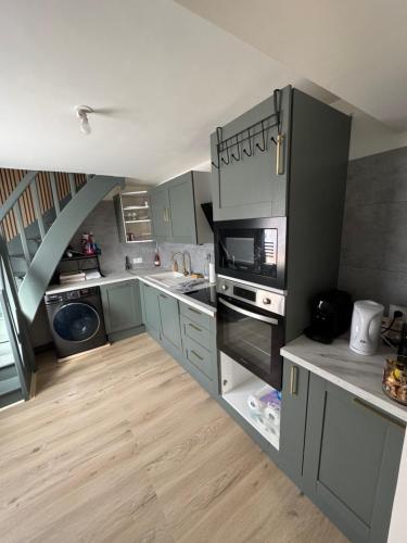 une grande cuisine avec des placards gris et un escalier dans l'établissement Maison de ville Saumur, à Saumur