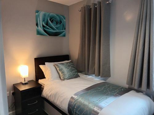 a small bedroom with a bed and a lamp at Silverlight's Place - 2BR Home in Central Oldbury in Oldbury