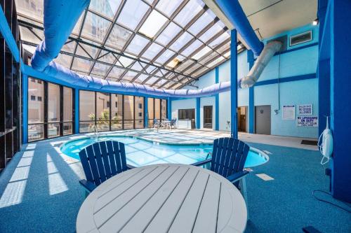 a building with a pool with two chairs and a table at Modern Oceanfront 1 Bedroom Condo, Prime Location, Stunning Views at Beach Cove Resort in Myrtle Beach