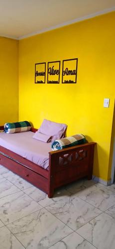 a bed in a yellow room with three signs on the wall at Dpto LUDIM 1 in Federación