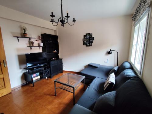 a living room with a black couch and a piano at Apartamento El Corazón de Gredos in Arenas de San Pedro