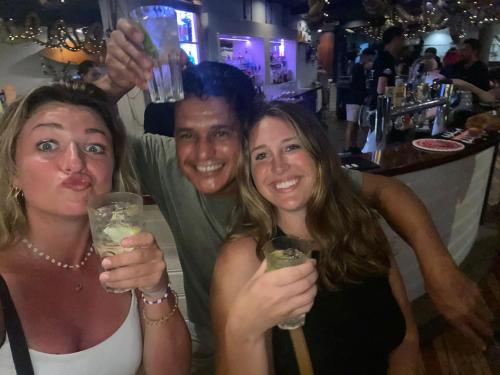 a man and two women holding up drinks at a bar at HOMESTYLE HOSTEL - 18-36yrs in Caloundra