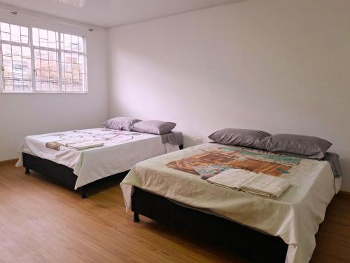 two beds in a small room with a window at Casa Bella Vista in Bogotá