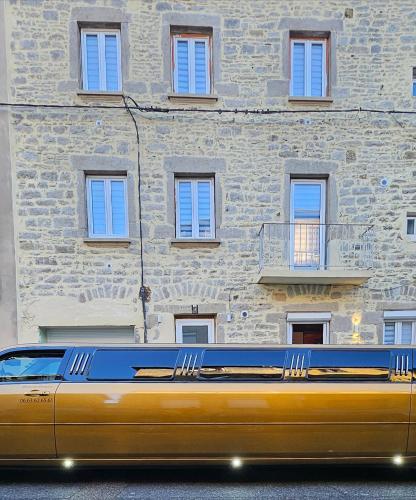 une limousine jaune garée devant un immeuble dans l'établissement LoveRoom by LimousineLyonnaise, à Rive-de-Gier