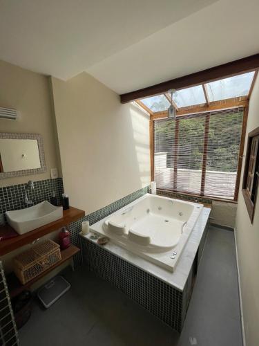 a large bathroom with a tub and a window at Cobertura em Itaipava in Araras Petropolis