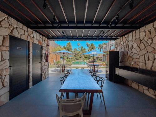 a dining room with a table and chairs and a stone wall at Villa Naluri - Casa Yodo - Apartamento 1 quarto em Japaratinga in Japaratinga