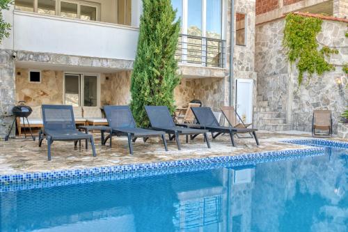 a pool with chairs and a table next to a house at Full Sea View Penthouse with Panoramic terrace in Prčanj
