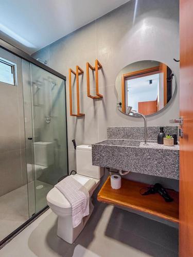 a bathroom with a toilet and a sink and a mirror at Villa Naluri - Casa Yodo - Apartamento 1 quarto em Japaratinga in Japaratinga