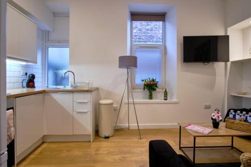 a kitchen with white cabinets and a table and a window at 2 bedroom, newly-renovated, comfortable town centre apartment! in Oban