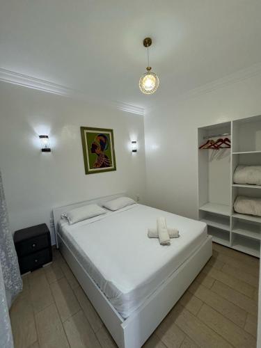 Un dormitorio blanco con una gran cama blanca y estanterías en Asunfo surf, en Tamraght Ouzdar