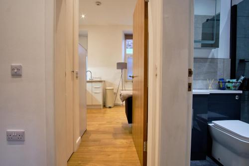 a hallway of a bathroom with a sink and a toilet at 2 bedroom, newly-renovated, comfortable town centre apartment! in Oban