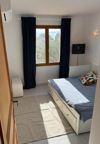 - une chambre avec un lit doté de rideaux bleus et d'une fenêtre dans l'établissement Maison Zen & Plage, à La Londe-les-Maures