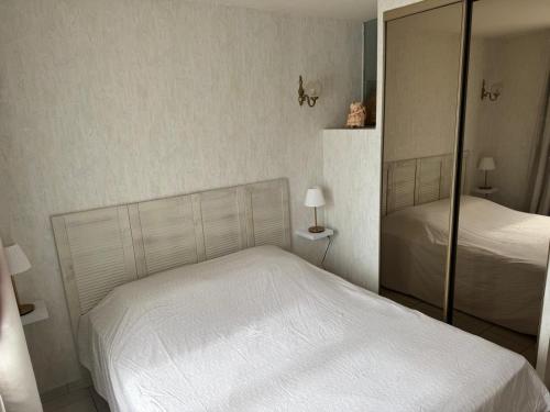 une chambre avec un lit blanc et un miroir dans l'établissement Maison Zen & Plage, à La Londe-les-Maures