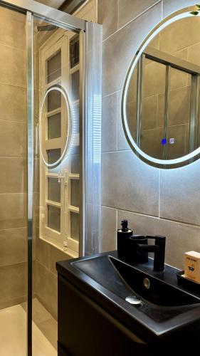 une salle de bain avec un lavabo noir et un miroir dans l'établissement Charmant Studio Rénové - Cœur Historique de Grasse - Climatisé & Tout Confort, à Grasse