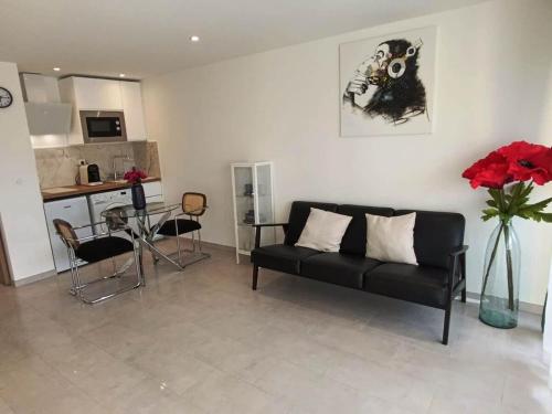 un salon avec un canapé noir et une cuisine dans l'établissement NOUVEAU ! Studio avec terrasse dans résidence en face de la mer - CANNES MIDI, à Cannes