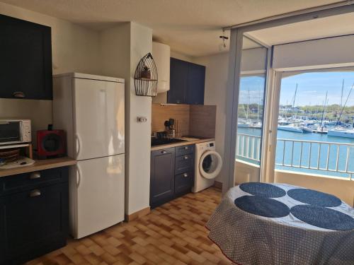 une cuisine avec un réfrigérateur et un balcon avec un bateau dans l'établissement Studio les pieds dans l'eau, au Cap d'Agde