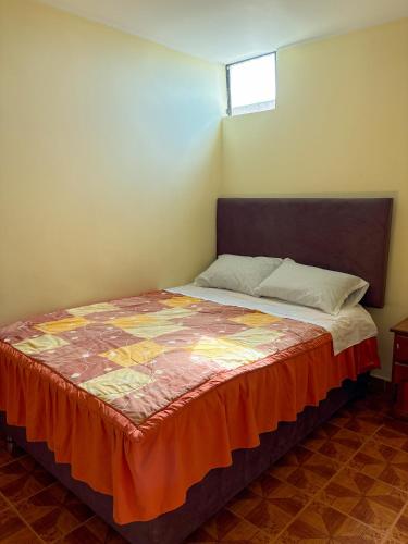 a bedroom with a bed with an orange blanket at Hospedaje Anais in Pisco