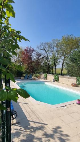 une grande piscine bleue avec des arbres en arrière-plan dans l'établissement Les Gîtes Mina, à Mosnes
