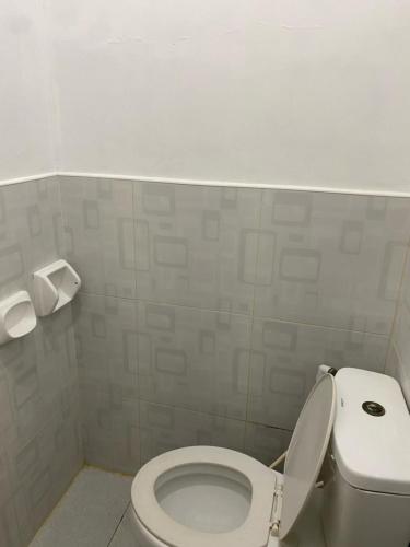 een badkamer met een toilet en een rol toiletpapier bij Happy Feet Siargao Homestay -General Luna in General Luna