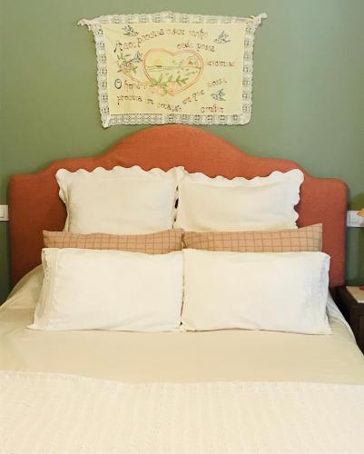 a bed with white pillows and a sign on the wall at Casa Bella para peregrinos- Charm House for pilgrims in A Guarda