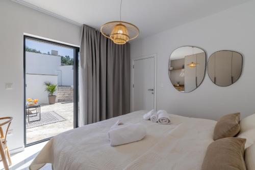a white bedroom with a large bed and two mirrors at Cocco e Limone in Sutivan