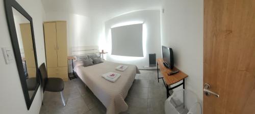 a small bedroom with a bed and a window at Departamento familiar in Caleta Olivia