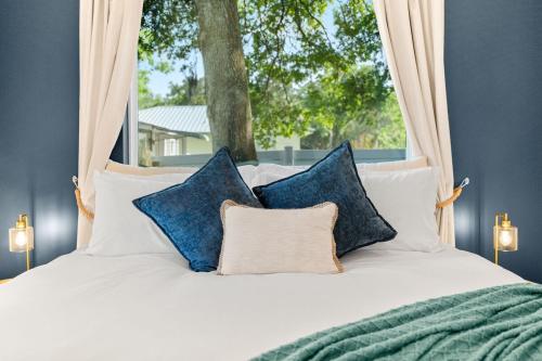a bed with blue and white pillows and a window at New-Dog Friendly,Hot Tub, Fire-pit, 1 mile to DTWN in Saint Augustine