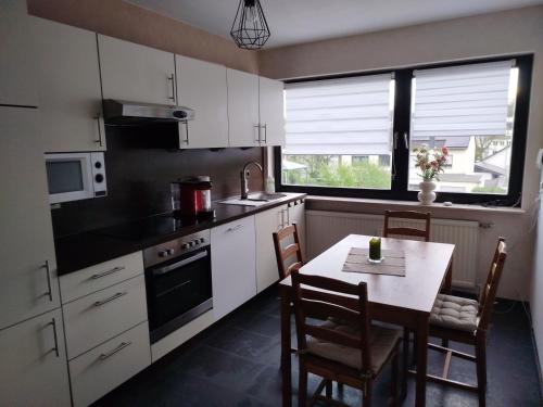a kitchen with white cabinets and a table with chairs at Ferienwohnung Zur goldenen Glocke in Mechernich