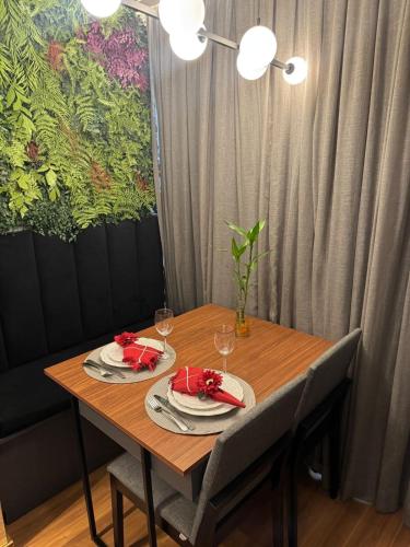a wooden table with two plates and wine glasses on it at Estúdio de Luxo Essenza in São Paulo