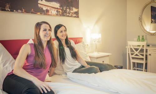 two young women sitting on a bed at La Cucina - Hotel & Restaurant in Peggau