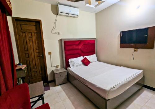 a bedroom with a bed with a red headboard at Doveinn Hotel R1 in Lahore