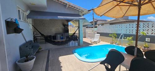 basen na patio z parasolem w obiekcie Casa em frente à praia em condominio w mieście Aracaju