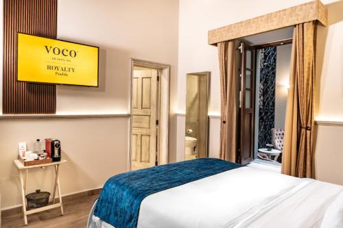 a room with a bed and a yellow sign on the wall at voco Royalty Puebla Downtown by IHG in Puebla