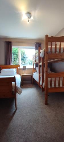 a bedroom with several bunk beds and a window at The Old Post Office House BnB in Balmacara