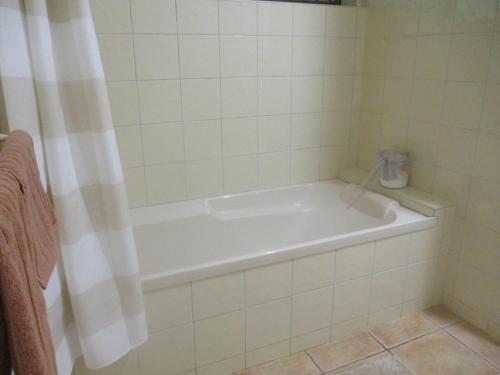a white bath tub in a bathroom with a shower curtain at Williams Lodge in Yungaburra