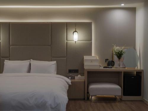 a bedroom with a bed and a desk with a laptop at Vibe Hotel Gimhae Jangyu in Gimhae