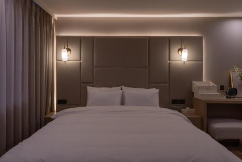 a bedroom with a large white bed with two lights at Vibe Hotel Gimhae Jangyu in Gimhae