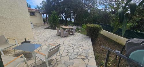 een patio met een tafel en stoelen en een tafel en stoelen bij Villa pied dans l eau in Cala dʼOro