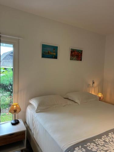 a white bedroom with a bed and a window at Moorea Sunset Beach in Haapiti