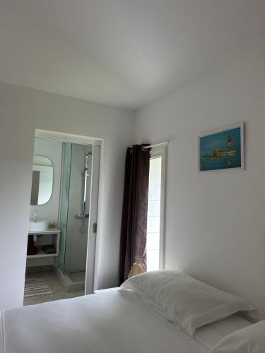 a white bedroom with a bed and a mirror at Moorea Sunset Beach in Haapiti