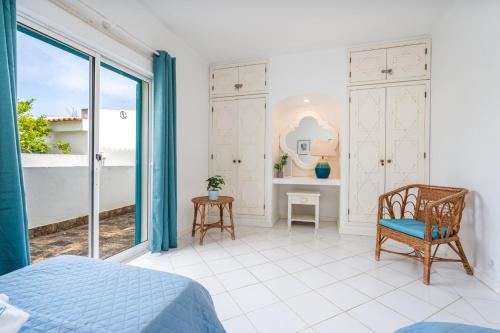 a bedroom with a bed and a chair and a window at Prainha Lounge in Alvor