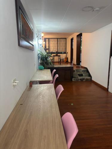 a long table with pink chairs in a room at Kuyay Yachi Hostel in Bogotá
